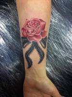 Tatuaje de un lazo con una rosa en el antebrazo