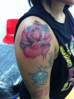 Rosa, diamante y mariposa tatuados en el brazo