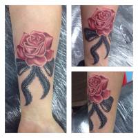 Tatuaje de un lazo con una rosa en el antebrazo