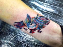 Tatuaje en la muñeca de un pájaro a color dibujado a pincel