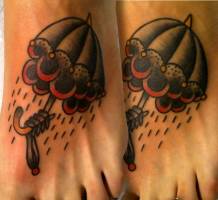 Tatuaje de una mano de esqueleto sujetando un paraguas con nubes dentro