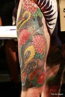 Tatuaje de una serpiente en la pierna entre flores y mariposas