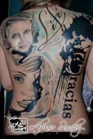Tatuaje en la espalda de una chica de caras de gente, con manchas de pintura, y las palabras Life y Gracias