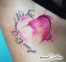 Tatuaje de un corazón con manchas de pintura y una frase