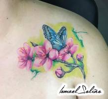 Tatuaje de una mariposa en una rama con flores