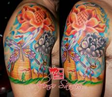 Tatuaje en el hombro de flores, arboles y una mariposa gigante