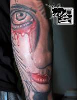 Tatuaje de una cara llorando sangre