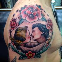 Tatuaje en el hombro de un marco de rosas con una pareja besándose