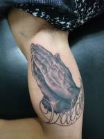 Tatuaje de unas manos rezando en el brazo