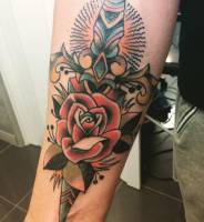 Tatuaje a color de una flor y una daga