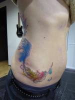 Tatuaje de una sirena zambulléndose con manchas de color