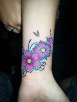 Tattoo de un par de flores a color con pétalos volando y una mariposa