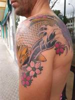 Tattoo japonés de una carpa saltando que ocupa omoplato y brazo