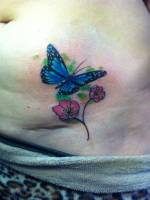 Tatuaje pequeño de una mariposa volando hacia una flor
