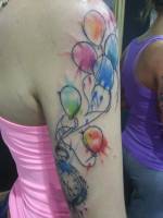Tattoo de globos pintados con manchas de color que levantan un reloj de bolsillo
