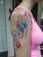 Tattoo de globos pintado con manchas de color en el brazo