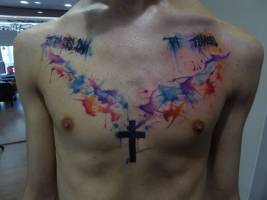 Tatuaje de una cruz en el pecho y una composición de manchas de pintura