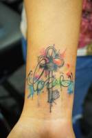 Tattoo de una llave con manchas de pintura y una palabra