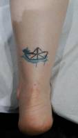 Tatuaje de un pequeño barco de papel con manchas de pintura
