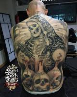 Tatuaje de un esqueleto rezando con tres calaveras con velas