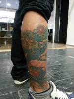 Tatuaje de un dragón enroscado en la pierna ed un chico