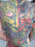 Tattoo de una cara de demonio hecha de fuego, en la espalda entera