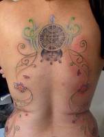 Tattoo de flores, lineas finas y símbolos en la espalda de una mujer