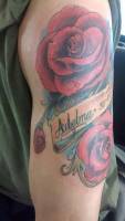 Tattoo de un par de rosas y una cinta con el nombre Adelma