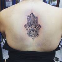 Tattoo de la jamsa en la columna de una mujer