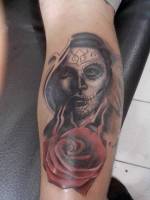 Tattoo de una mujer pintada de calavera mexicana y una rosa