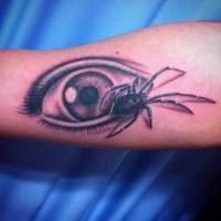 Tattoo de una araña andando al lado de un ojo abierto