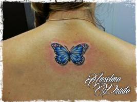 Tattoo de una mariposa en la columna de una mujer