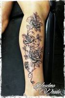 Tatuaje de rosas en blanco y negro por la pierna de una mujer