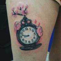Tattoo de un reloj con una rama y algunas flores